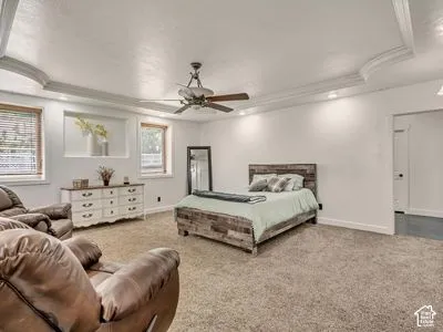Tray ceiling with crown molding, recessed lighting, central ceiling fan, and built-in wall niche