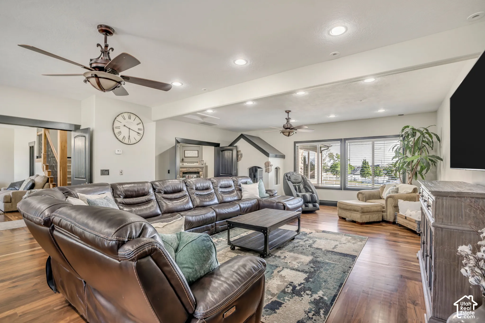 Wood-finish flooring, recessed ceiling lighting, two dual-blade ceiling fans, and expansive windows