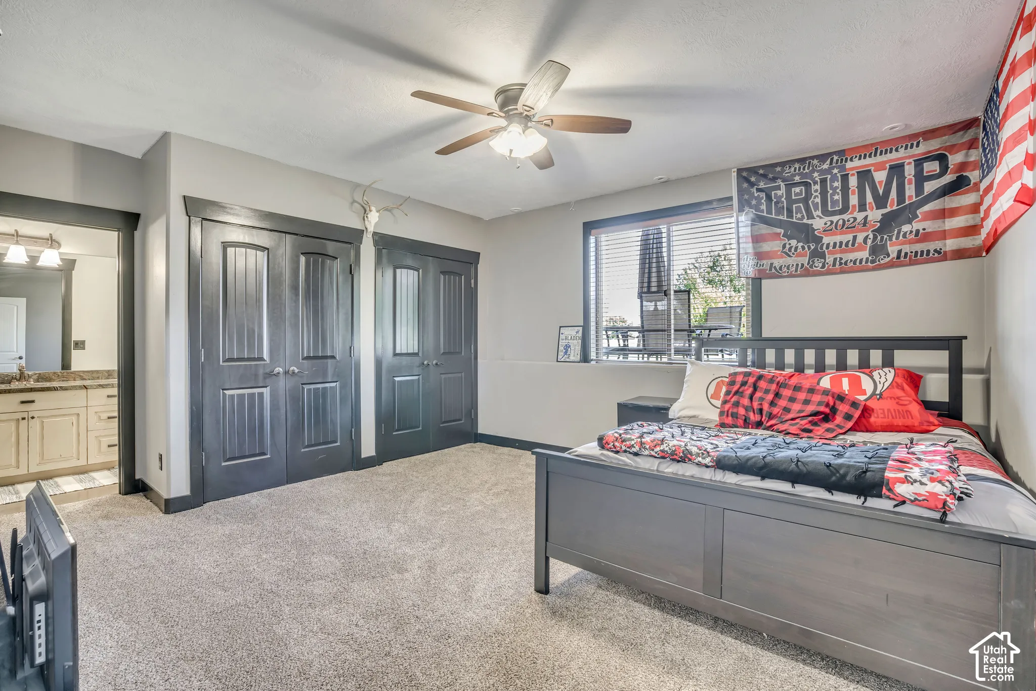 Room featuring neutral wall tones, dual interior doors with dark trim, carpeted flooring, and a ceiling fan with integrated lighting