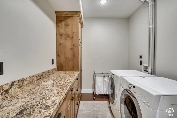 Laundry area featuring custom wood cabinetry, stone-finish countertops, and wood-finish flooring