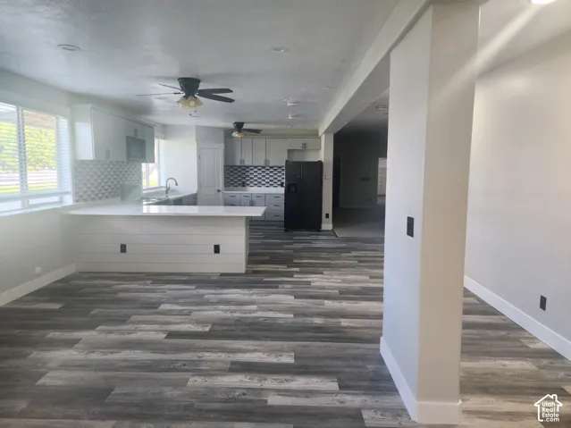 Kitchen featuring white cabinetry, quartz countertops, a shiplap-accented island, geometric tile backsplash, and wood-finish flooring