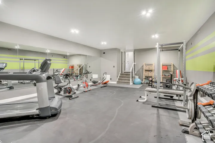 Finished room featuring large wall-mounted mirrors, recessed lighting, and rubber flooring
