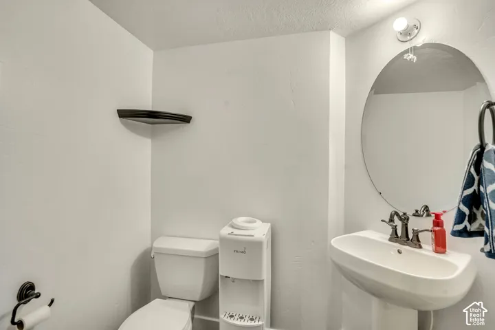 Wall-mounted oval mirror, pedestal sink with multi-handle faucet, built-in corner shelving, and oil-rubbed bronze hardware