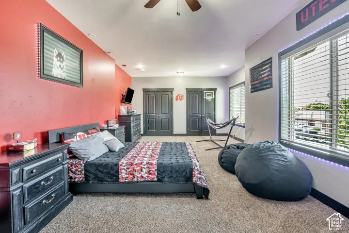 Spacious room featuring a vaulted ceiling, dual interior doors, large windows with horizontal blinds, neutral carpeting, and recessed lighting