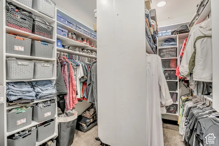 Walk-in closet featuring extensive built-in white shelving, multiple hanging rods, and recessed ceiling lighting