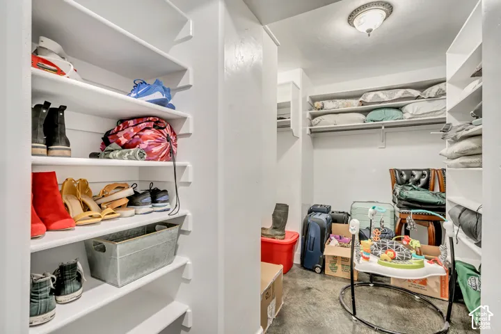 Walk-in storage area featuring white built-in shelving and flush-mount ceiling lighting