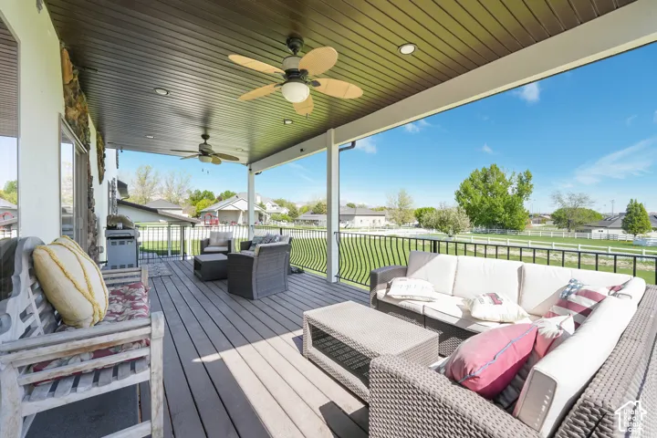 Covered porch featuring wood-finish decking, dark-toned horizontal beadboard ceiling, recessed lighting, ceiling fans, and black metal railing