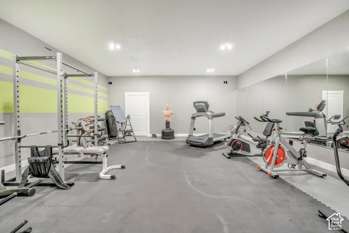 Finished interior space featuring recessed lighting, a full-length wall mirror, neutral paint, and specialized floor surfacing