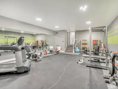 Spacious room featuring floor-to-ceiling wall mirrors, recessed lighting, and industrial-grade rubberized flooring