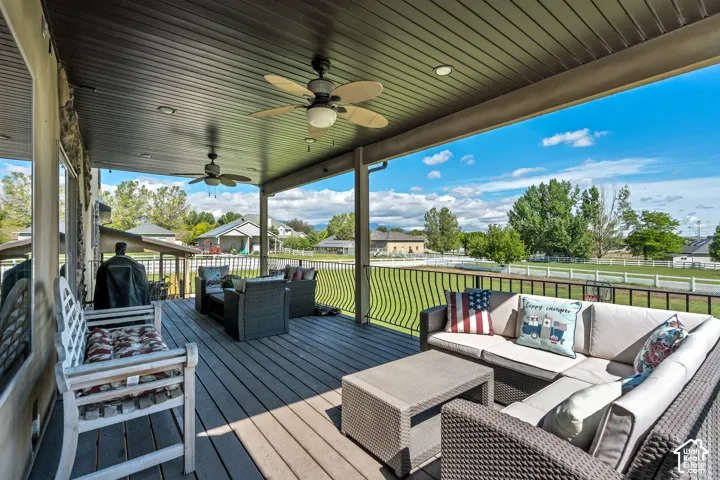 Covered deck featuring wood-composite decking, a dark paneled ceiling with recessed lighting, ceiling fans, and metal railing