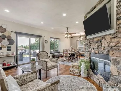 Floor-to-ceiling natural stone fireplace, recessed lighting, wood-finish flooring, and glass sliding doors leading to an exterior space