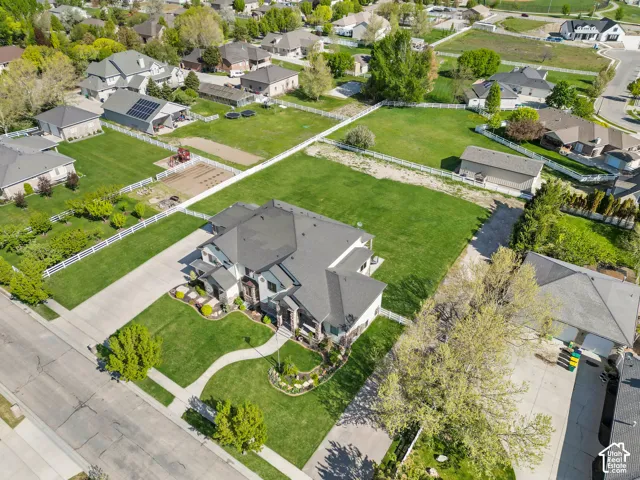 Aerial perspective featuring an expansive lot, manicured lawn, multi-gabled roofline, concrete driveway, and white perimeter fencing