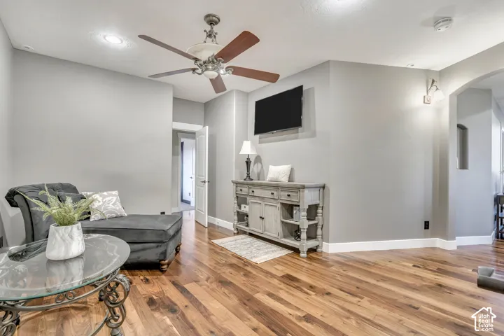 Wood-finish flooring, recessed lighting, arched entryway, and ceiling fan with integrated light fixture