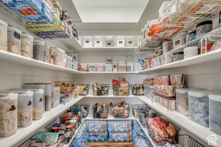 Walk-in pantry featuring white shiplap walls, multi-level fixed shelving, wire storage racks, and overhead recessed lighting