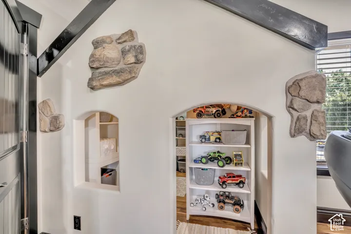 Vaulted ceiling with exposed dark-toned beams, arched wall cutouts, and decorative stone masonry accents