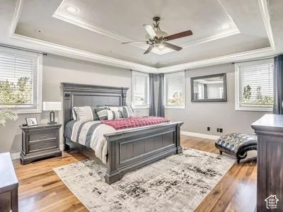 Tray ceiling with recessed lighting, wood-finish flooring, and a multi-blade ceiling fan