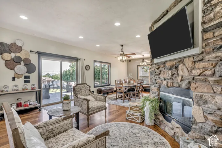 Floor-to-ceiling stone fireplace, wood-finish flooring, recessed lighting, and sliding glass door