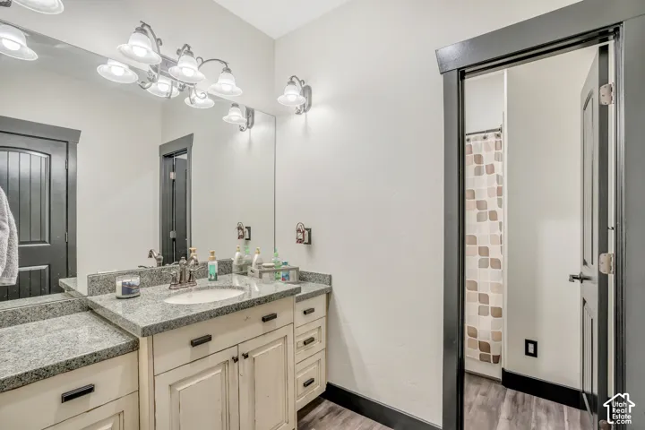 Bathroom vanity featuring a stone-composite countertop, undermount sink, multi-drawer cabinetry, full-width mirror, and multi-light wall fixture with contrasting dark trim