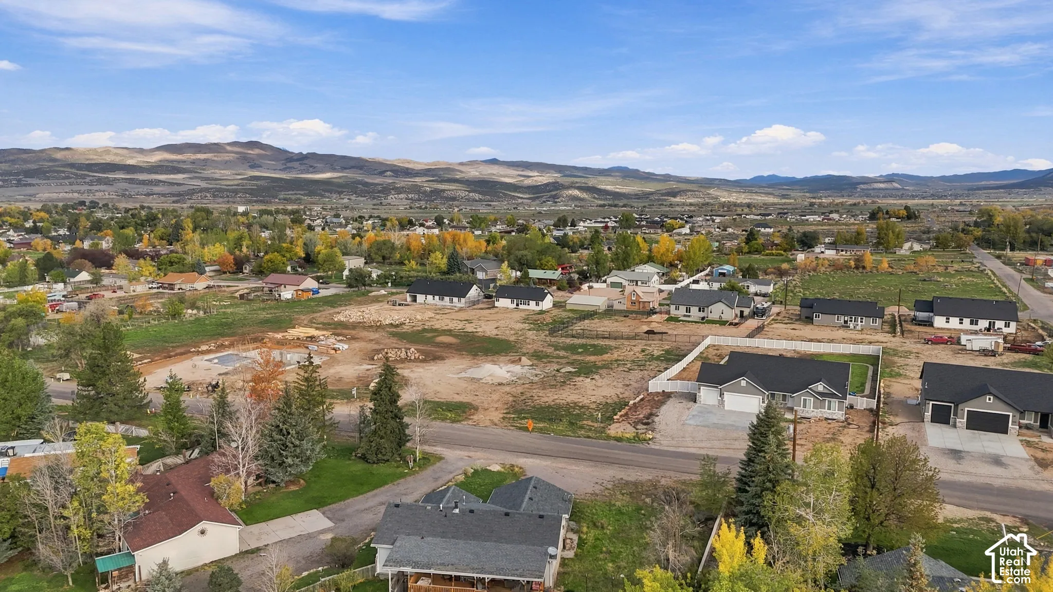 Aerial perspective featuring mountain backdrops and a residential setting with paved streets and mature trees