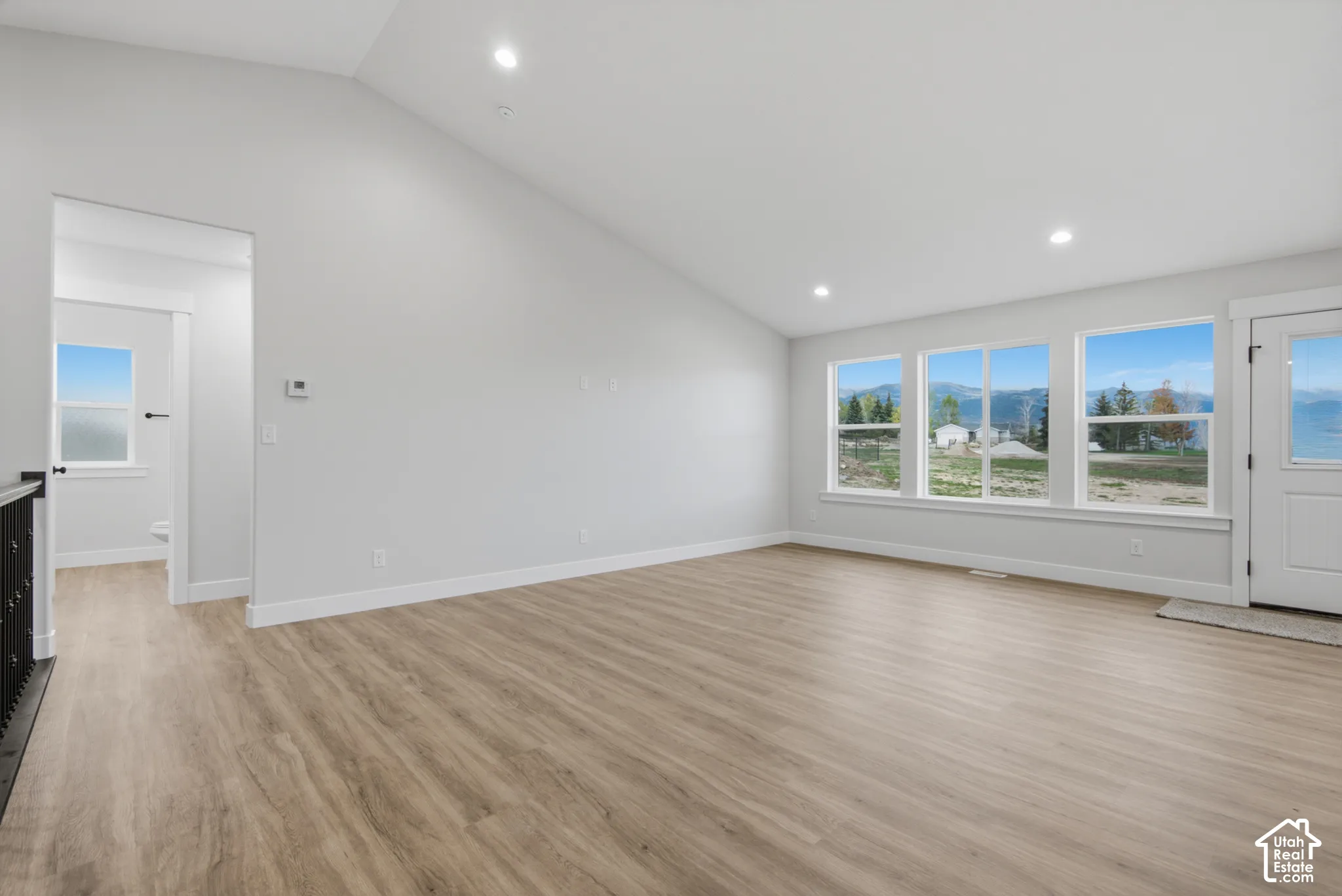Vaulted ceilings, wood-finish flooring, recessed lighting, and expansive windows featuring a mountain backdrop