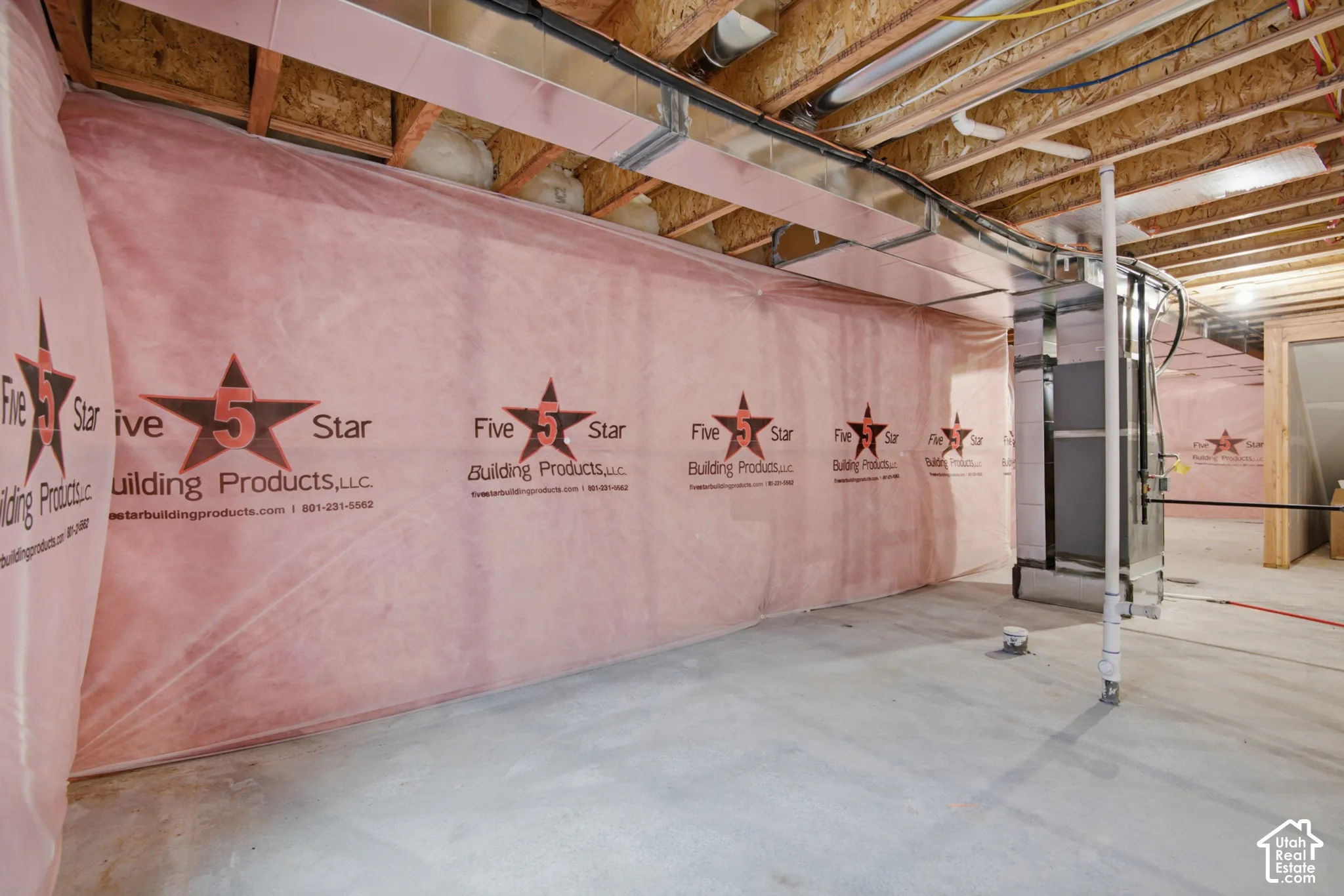 Unfinished lower level featuring concrete flooring, exposed wooden ceiling joists, metal ductwork, and wall insulation wrap