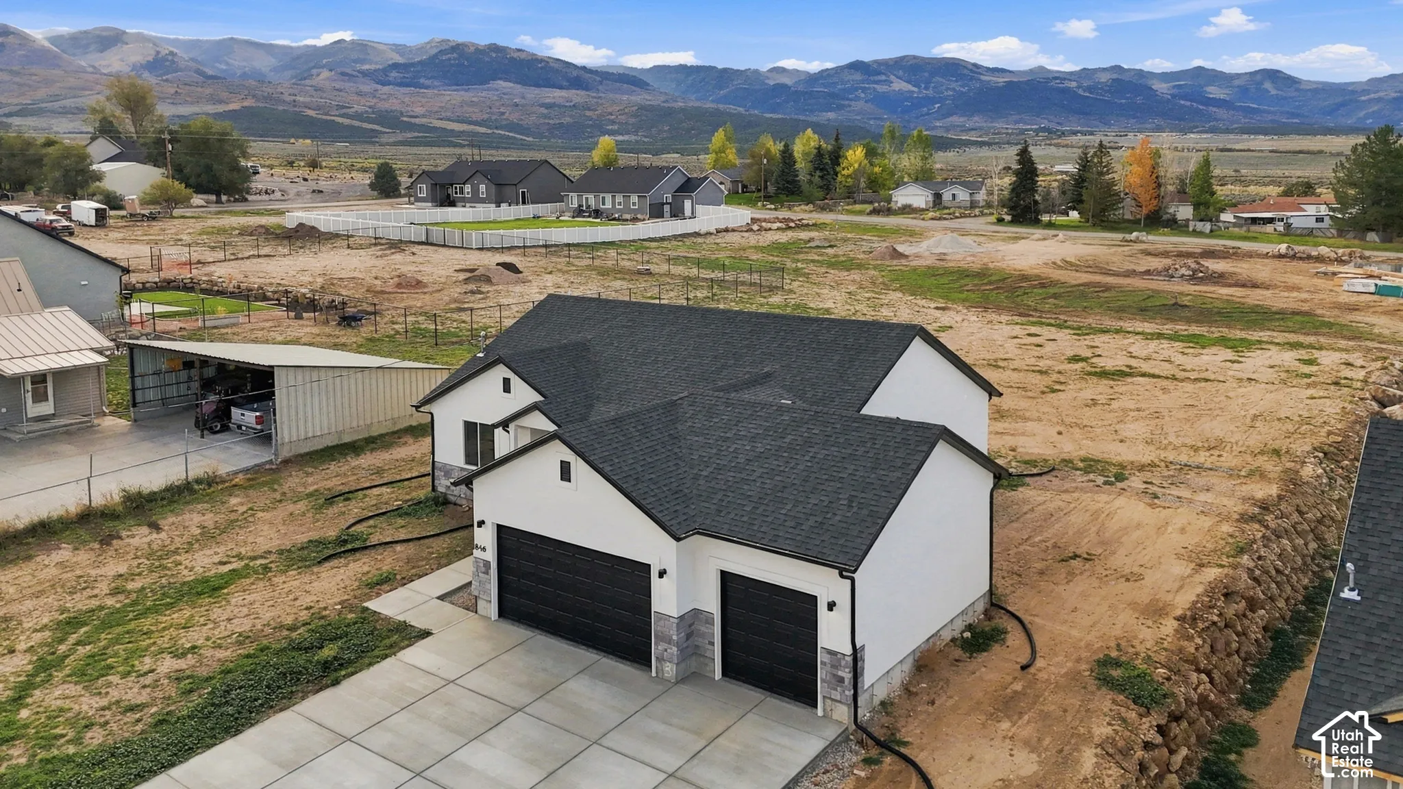 Single-story residence featuring a multi-gabled asphalt shingle roof, two-car garage with black paneled doors, stone veneer accents, and an expansive mountain backdrop