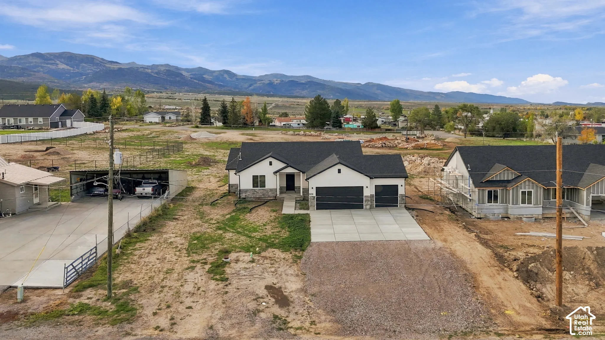 Single-story residence featuring a stone and siding exterior, asphalt shingle roof, attached multi-car garage, concrete driveway, and mountain backdrop