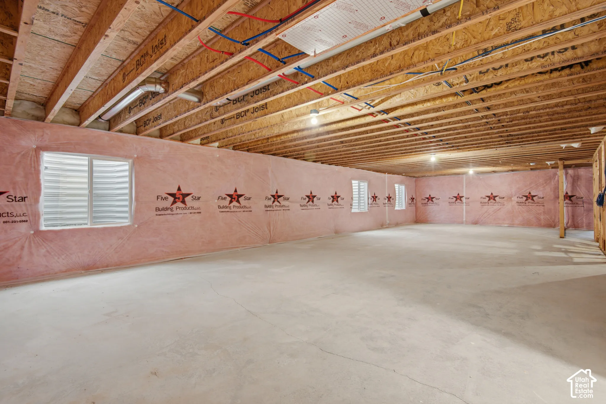 Unfinished lower level featuring exposed wood joist ceilings, concrete flooring, perimeter insulation, and multiple egress windows