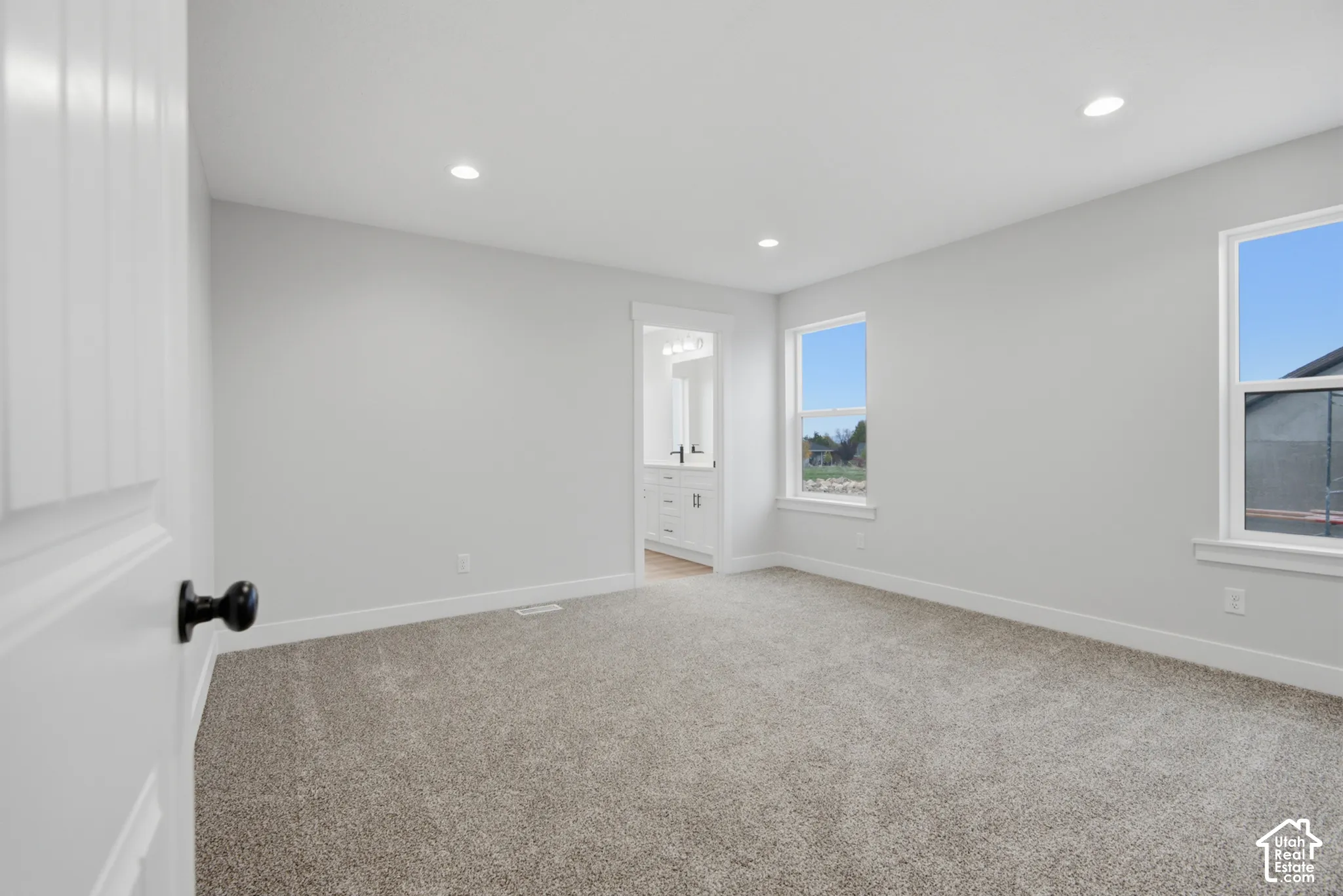 Neutral-toned carpet, recessed ceiling lighting, two double-hung windows, and crisp wall finishes