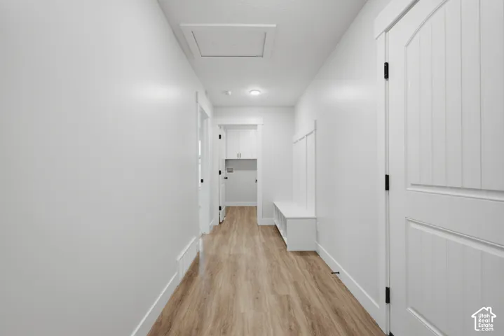 Hallway featuring wood-finish flooring, white paneled doors with black hardware, built-in storage bench with board-and-batten detailing, and recessed ceiling lighting