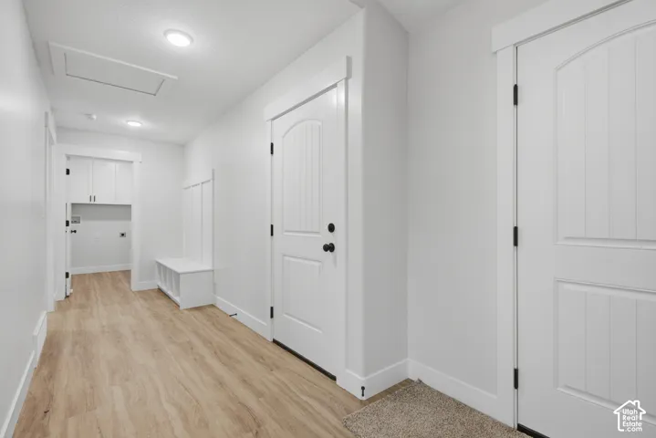 Interior space featuring wood-finish flooring, white paneled doors with matte black hardware, built-in storage bench with beadboard detailing, and recessed ceiling lighting