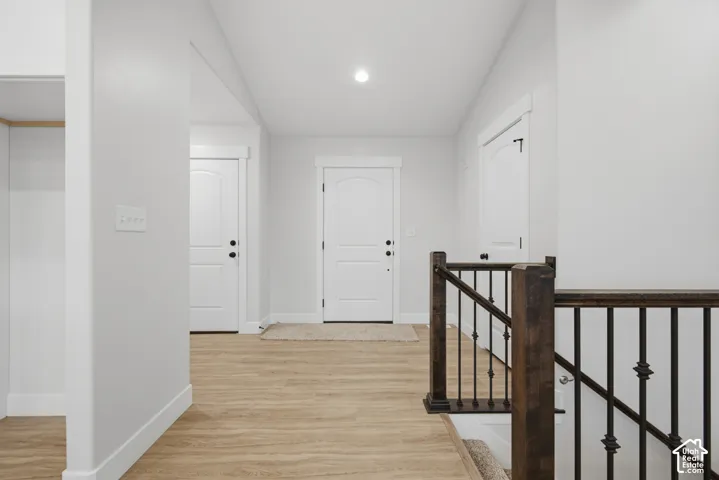 Interior featuring wood-finish flooring, two-panel arched doors, recessed lighting, and a staircase with stained wood handrails and black metal balusters