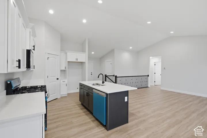 Kitchen featuring white shaker-style cabinetry, quartz countertops, a central island with a matte black faucet, vaulted ceilings, and wood-finish flooring