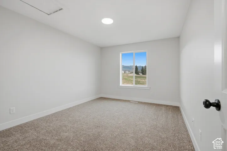 Neutral-toned interior space featuring neutral carpeting, a single-pane window with mountain scenery, a recessed ceiling light, and a matte black door handle