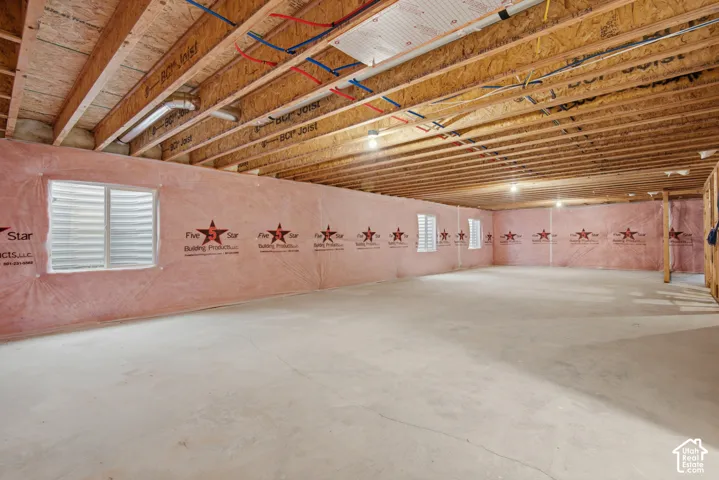 Unfinished lower level featuring exposed wood joist ceilings, concrete flooring, perimeter insulation, and multiple egress windows