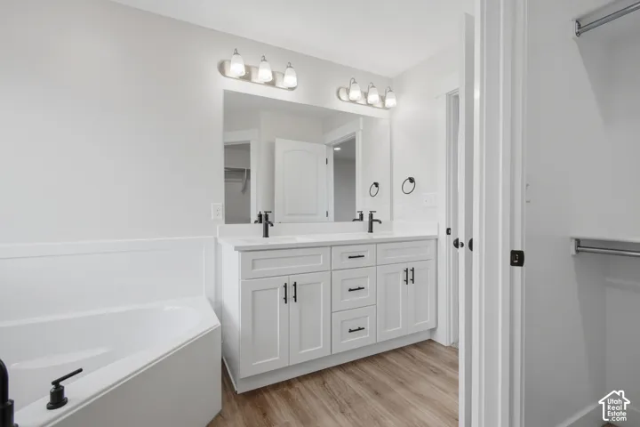 Double vanity featuring white cabinetry, black hardware, dual sinks, and a large wall-mounted mirror