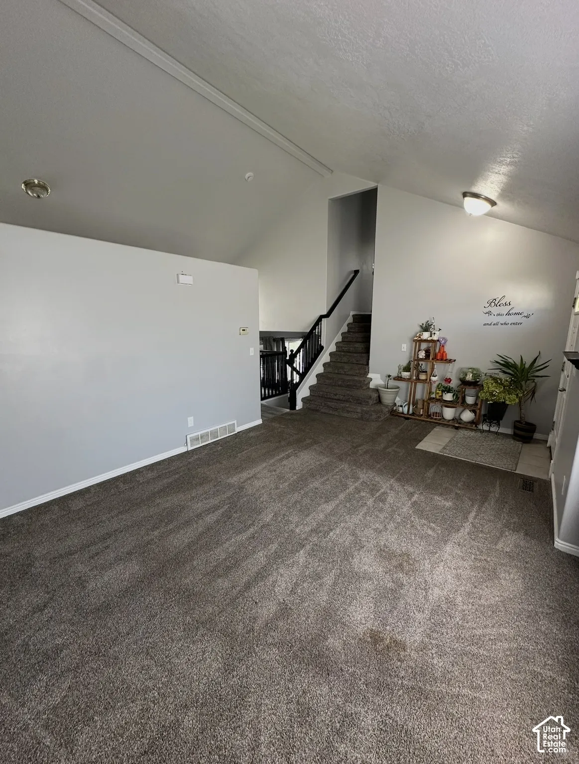Vaulted ceiling featuring neutral wall paint, carpeting, staircase with a dark-finish handrail, and recessed lighting