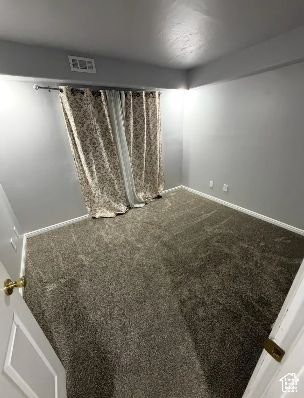 Neutral-toned interior room featuring wall-to-wall carpeting and soft gray wall paint