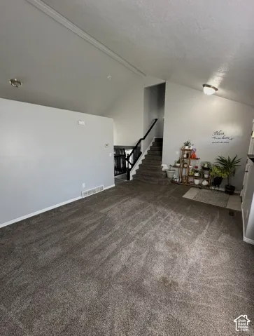 Vaulted ceiling featuring neutral wall paint, carpeting, staircase with a dark-finish handrail, and recessed lighting