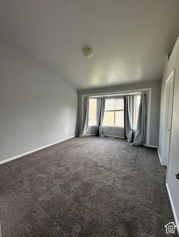 Room featuring neutral wall tones, wall-to-wall carpeting, and a multi-panel bay window
