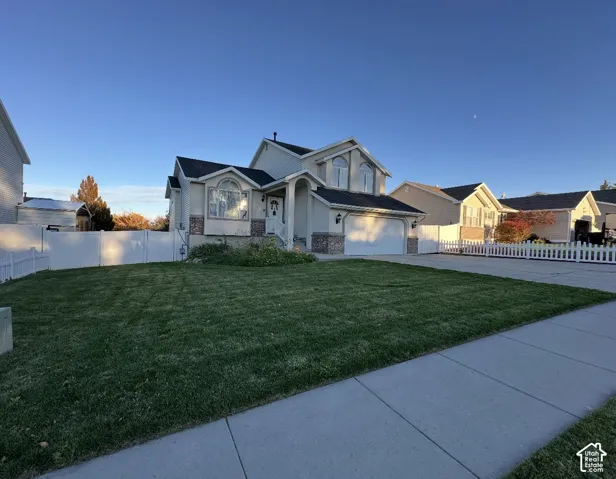 Two-story residence featuring a multi-gabled roofline, stone veneer accents, arched windows, and a concrete driveway