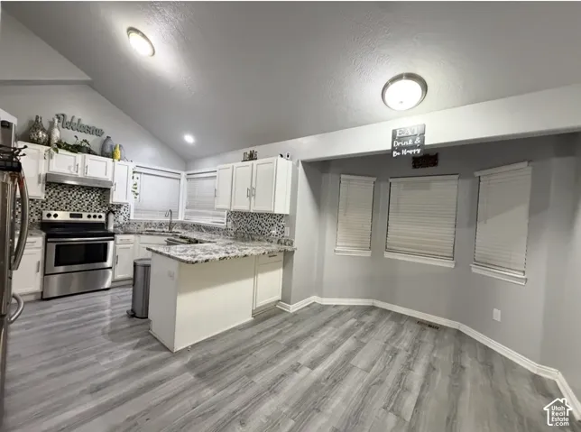 Kitchen featuring white cabinetry, stone-finish countertops, mosaic tile backsplash, wood-finish flooring, and a vaulted ceiling