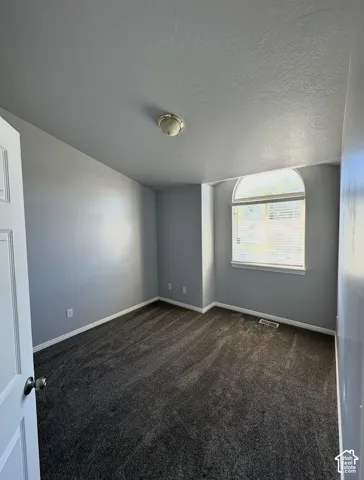 Room featuring vaulted ceilings, neutral-toned carpeting, and an arched window