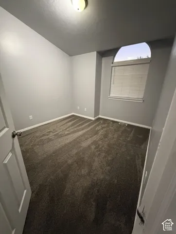Room featuring vaulted ceilings, neutral-toned wall paint, plush carpeting, and an arched window with integrated blinds