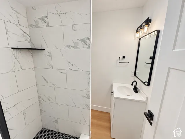 Shower featuring large-format veined tile walls and a hexagonal tile floor, paired with a white vanity, matte black fixtures, and a black-framed vanity mirror