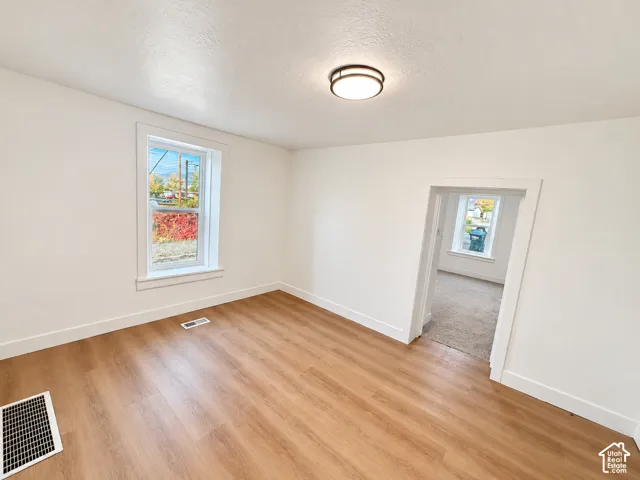 Interior room featuring wood-finish flooring, white walls, a flush-mount circular light fixture, and a large window with white trim