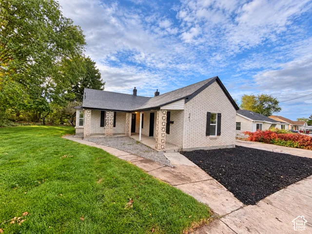 Light brick exterior featuring decorative masonry columns, gabled roofline, dark shutter accents, and a concrete driveway