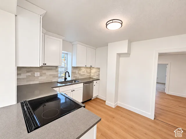 Kitchen featuring white cabinetry, solid-surface countertops, horizontal tile backsplash, stainless steel appliances, and wood-finish flooring