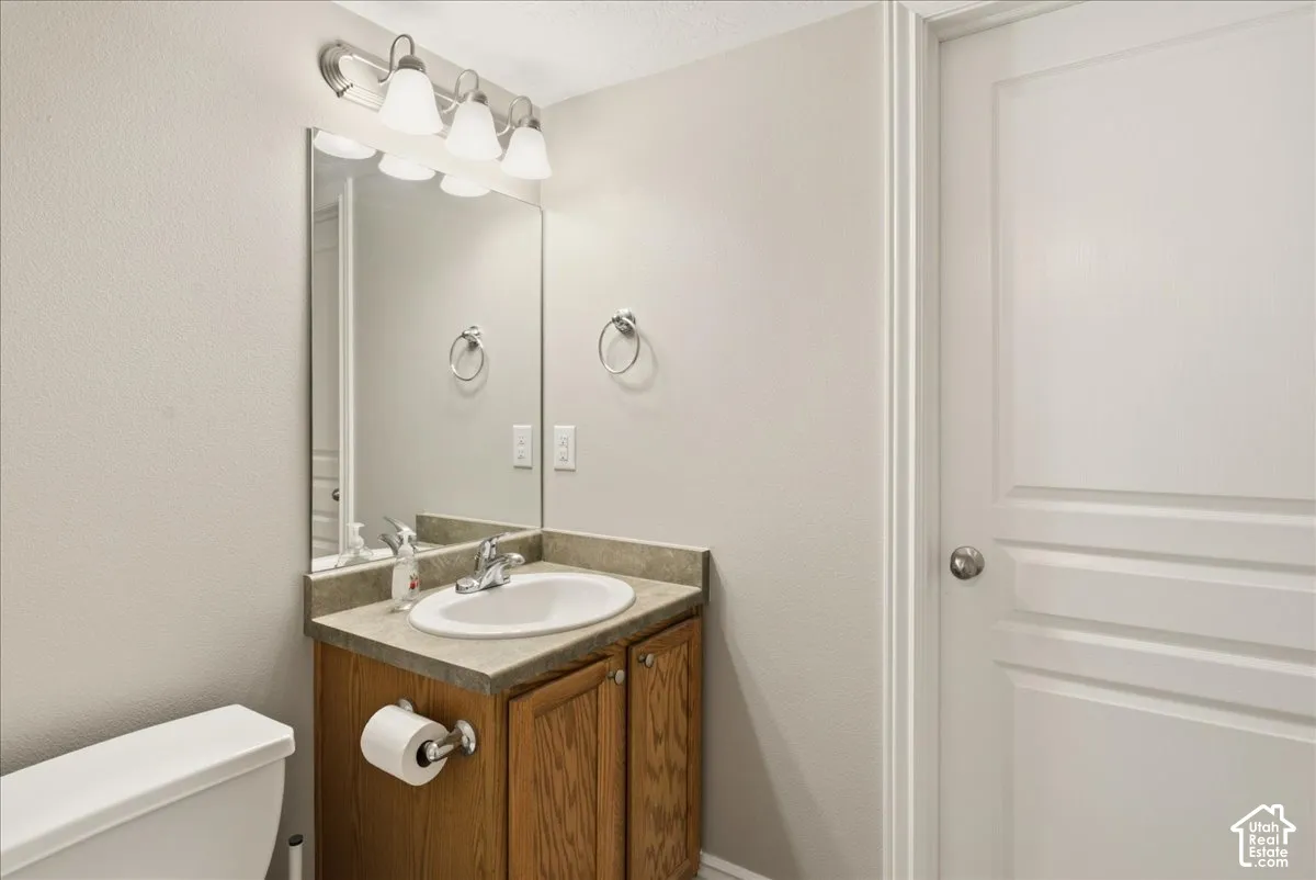 Vanity with a solid surface countertop, integrated oval basin, polished metal faucet, wall-mounted four-light fixture, and a large rectangular mirror