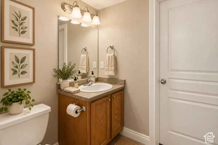 Bathroom featuring a vanity with wood cabinetry, an integrated sink with a stone-finish countertop, a wall-mounted four-light fixture, and a rectangular mirror